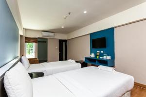 曼那Solace at Srinakarin Hotel的一间酒店客房,设有两张床和电视