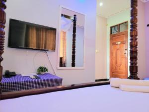 达累斯萨拉姆Jm Lodge - Kunduchi的一间设有床铺和墙上电视的客房