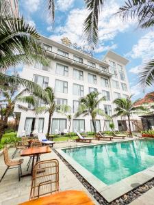 绥和市Sala Tuy Hoa Beach Hotel的一座拥有游泳池和棕榈树的酒店