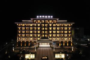 彭泽彭泽远洲轩廷酒店的一座大建筑,上面有灯,晚上