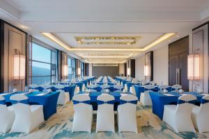 彭泽彭泽远洲轩廷酒店的一个带蓝色桌子和白色椅子的大型宴会厅