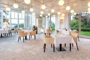 ErmatingenLILIENBERG的餐厅设有白色的桌椅和窗户。