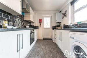 利Firs Serviced Accommodation的厨房配有白色橱柜、洗衣机和烘干机