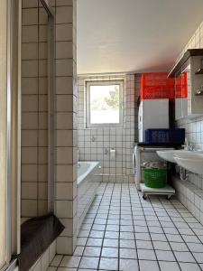 比勒费尔德WinWin im Westen的浴室铺有白色瓷砖地板,配有浴缸和水槽。