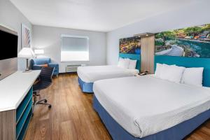 圣安东尼奥Days Inn & Suites by Wyndham San Antonio near Frost Bank Center的酒店客房配有两张床和一张书桌