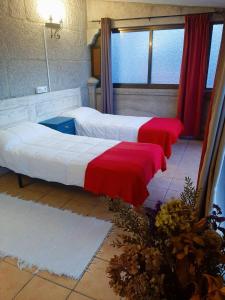 图伊Albergue Villa San Clemente的客房内的两张床,配有红色和白色床单