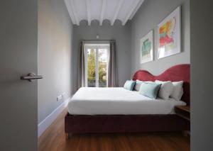 塞维利亚numa I Prestigio Apartments的一间卧室配有一张带红色床头板的床和窗户