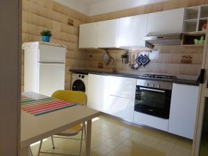 新福卡Casa Vacanza Olimpia的厨房配有白色橱柜、桌子和冰箱。