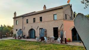 Trecastelli"La Casa degli ulivi Art B&B"的一座大型砖砌建筑,前面设有桌子