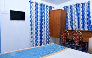 蒙纳Blackcherry Munnar的一间卧室配有蓝色窗帘、一张床和电视。