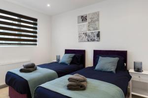 The HydeStar London Station Road 3-Bed Oasis with Garden的一间卧室配有两张带毛巾的床