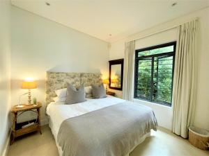 普利登堡湾Dageraad的白色的卧室设有一张大床和一个窗户