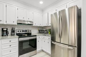 默特尔比奇Seascape 109的厨房配有白色橱柜和不锈钢冰箱