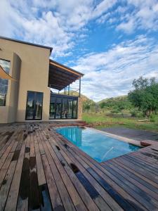 兰斯堡Pilanesberg Private Lodge的一座带木甲板和游泳池的房子