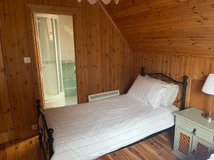 DuneenaLarge Newly Refurbished Lakeside Chalet With Optional Hot Tub & Boat Hire的木制客房内的一间卧室,配有一张床