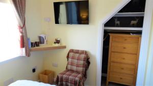 Port na LongBracadale House的一间卧室配有椅子和带电视的梳妆台。