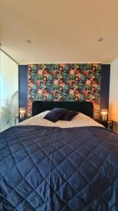 奥斯坦德Maui - zeezichtappartement te Oostende的一间卧室配有一张蓝色的床和花卉墙