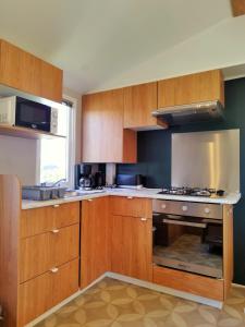 瓦尔拉普拉日Mobil-Home Eucalyptus Valras-Plage的厨房配有木制橱柜和炉灶烤箱。