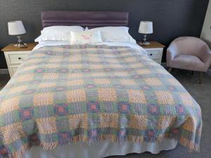 卡纳芬Samuel cottage的一张带彩色毯子和椅子的床