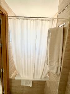 多列毛利诺斯Hotel Cabello的配有白色淋浴帘和毛巾的淋浴