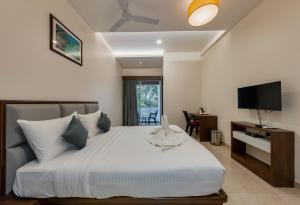 KudālHotel Aaradhya Adorer的卧室配有白色的床和电视。