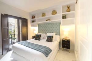 马拉加THE CLOCK HOUSE Luxury Urban Suites的一间带大床的卧室和一个阳台