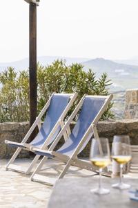 米克诺斯城Villa Azzuro II - Mykonianvilla的一张桌子上的椅子,放两杯葡萄酒