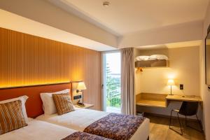 马亚Hotel 3K Porto Aeroporto的配有一张床、一张书桌和一扇窗户的酒店客房