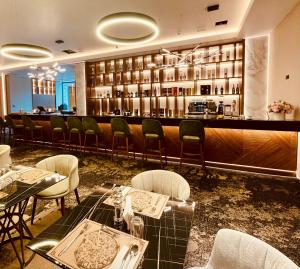 锡纳亚Hotel Alexandrion Experience的餐厅设有酒吧,配有桌椅