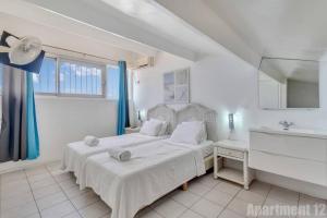 克拉伦代克博内尔岛海滨公寓的白色卧室设有两张床和水槽