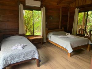 比加瓜Cataratas Bijagua Lodge, incluye tour autoguiado Bijagua Waterfalls Hike的配有木墙和窗户的客房内的两张床