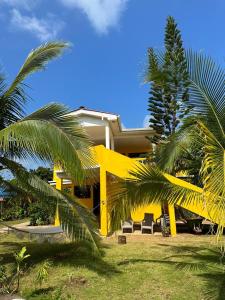 小玉米岛Sunshine Hotel Little Corn Island的棕榈树前方的黄色房子