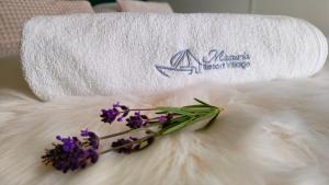 ŻywkiMasuria Resort Village, całoroczne domki z widokiem na jezioro, sauna i jacuzzi的一条毛巾,上面有一条白色毯子,上面有一大束紫色的鲜花