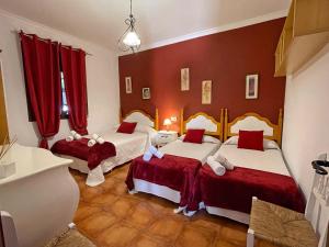 埃尔加斯托尔JARANDALUS (casa con atractivo y encanto)的配有红色窗帘的客房内的两张床