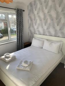 SilebyRatcliffe House - Spacious 3 bedroom House in Sileby的一张带两条毛巾的床和窗户