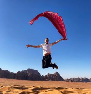 瓦迪拉姆Wadi Rum nature的一个人在沙漠中用红色降落伞跳跃