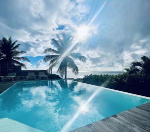 圣安尼Villa Estheria的一座蓝色的游泳池,上面有棕榈树和大海