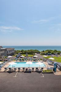 蒙托克哈特曼布里尼微风海滩度假汽车旅馆的一个带游泳池和遮阳伞的停车场,以及大海