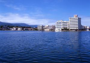 佐渡市湖畔之宿吉田屋酒店的一大片水体,有建筑背景