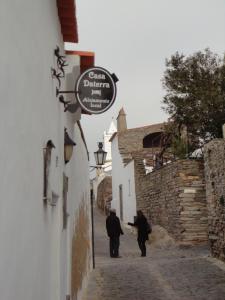 蒙萨拉什Casa Daterra的两个人在楼房的一条小巷里走着,上面有标志