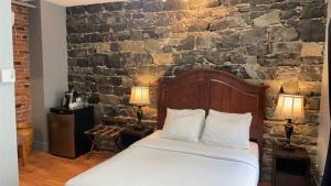 魁北克市逸轩综合酒店的一间卧室设有一张床和石墙