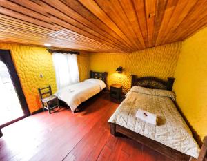 El CocuyHotel Museo la Posada del Molino的一间卧室设有两张床,铺有木地板