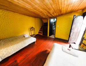 El CocuyHotel Museo la Posada del Molino的配有黄色墙壁和木地板的客房内的两张床