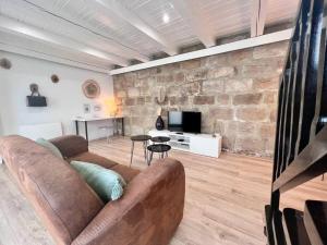 布里夫拉盖亚尔德Casa Bondy - Sublime T2 Refait à Neuf - Hyper Centre de Brive的带沙发和石墙的客厅