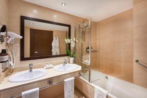 莱昂莱昂市长广场NH系列酒店的浴室设有2个盥洗盆、淋浴和镜子。