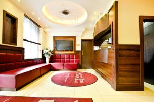 伦敦国王十字客栈酒店的一间设有红色沙发和电视的等候室