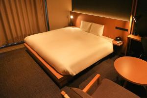 东京N+ Hotel 秋叶原的酒店客房设有一张大床和一张桌子。