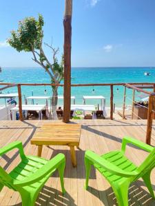 布兰卡滩SUNSET BEACH的海滩上的两张绿色椅子和一张木桌
