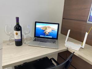 坎普斯戈伊塔卡济斯Flat aconchegante próximo a Pelinca的一张桌子上的笔记本电脑,上面放着一瓶葡萄酒