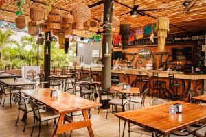 坎昆Nomads Hotel, Hostel & Rooftop Pool Cancun的一间带桌椅的餐厅和一间酒吧
